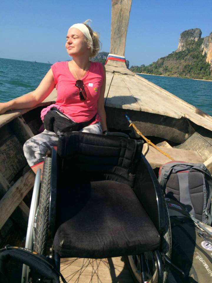 Angelika Chrapkiewicz-Gądek w Tajlandii na drewnianej łodzi. Wygrzewa się w słońcu a przed nią stoi wózek