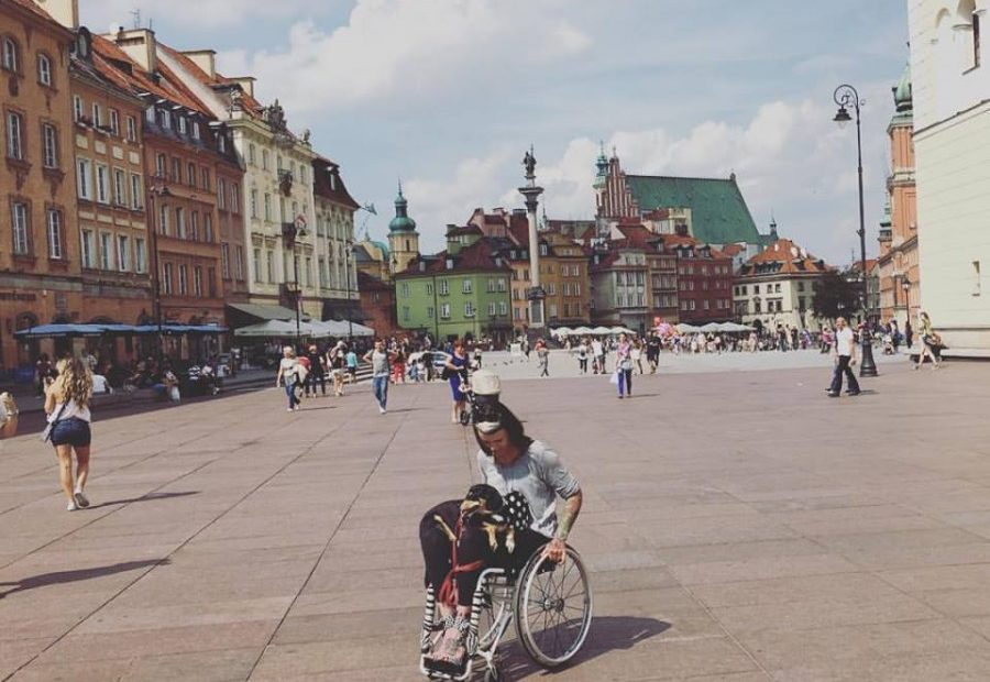 Izabela Sopalska-Rybak, poruszająca się na wózku z psem na kolanach, na starówce.
