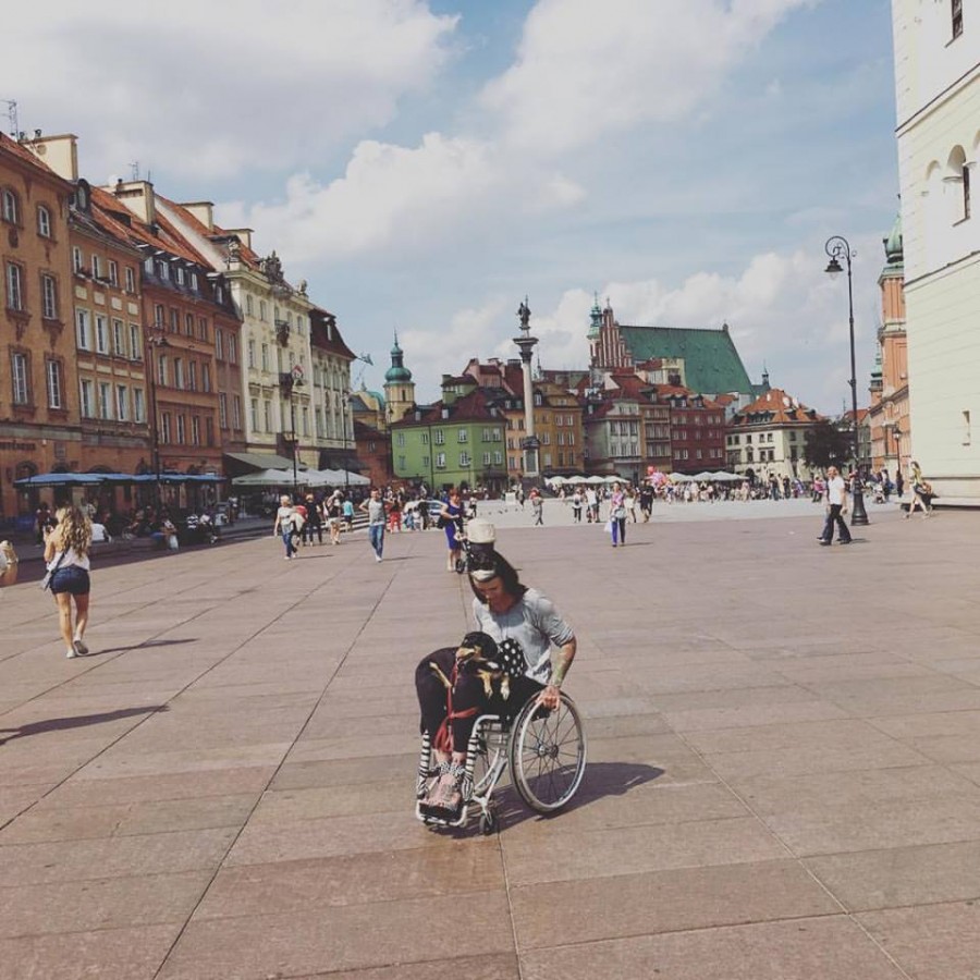 Izabela Sopalska-Rybak, poruszająca się na wózku z psem na kolanach, na starówce.